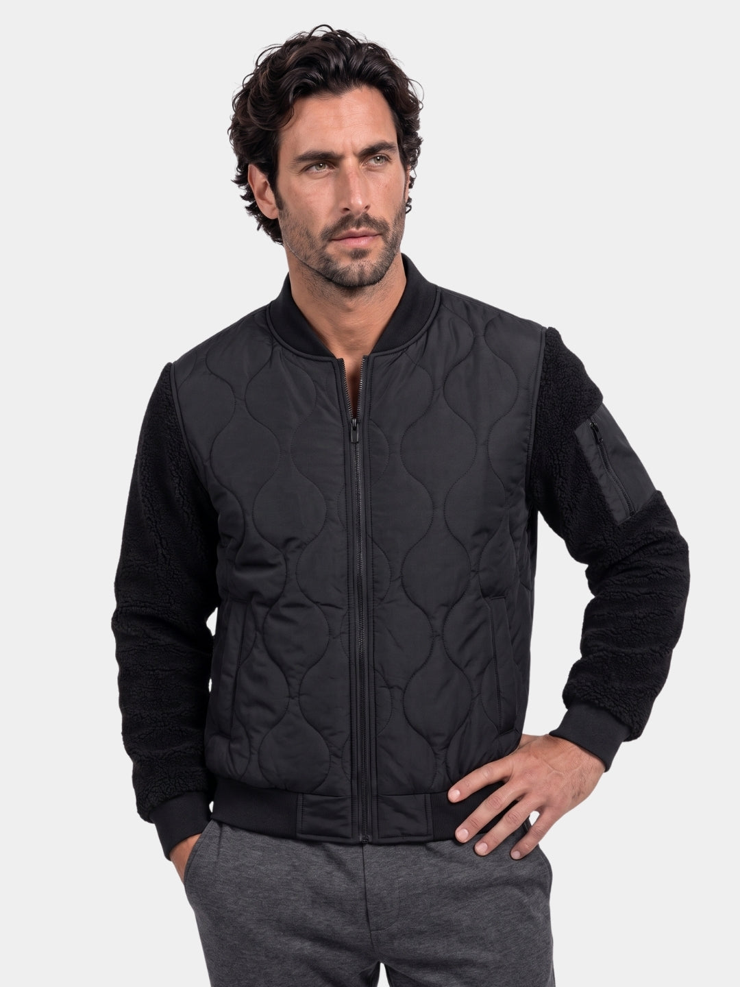 Man wearing black quilted bomber jacket with sherpa sleeves, front view, Cross & Crown