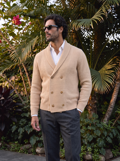 Man wearing beige shawl cardigan outdoors among palm trees