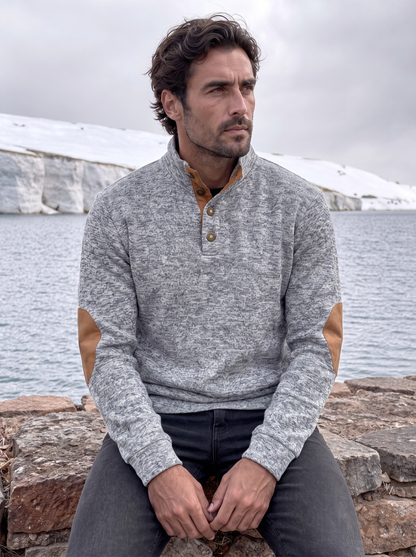 Man wearing the heathered gray pullover near the coast