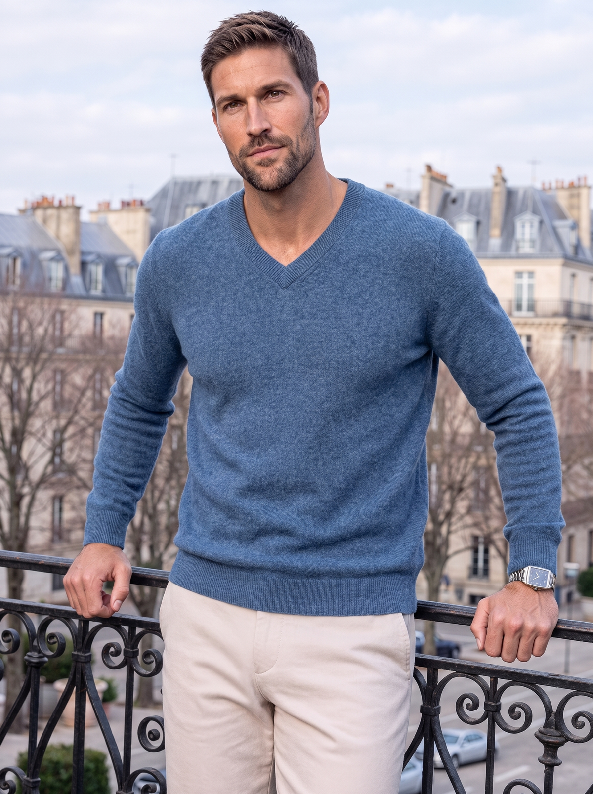 Man in the blue V-neck sweater on a city balcony