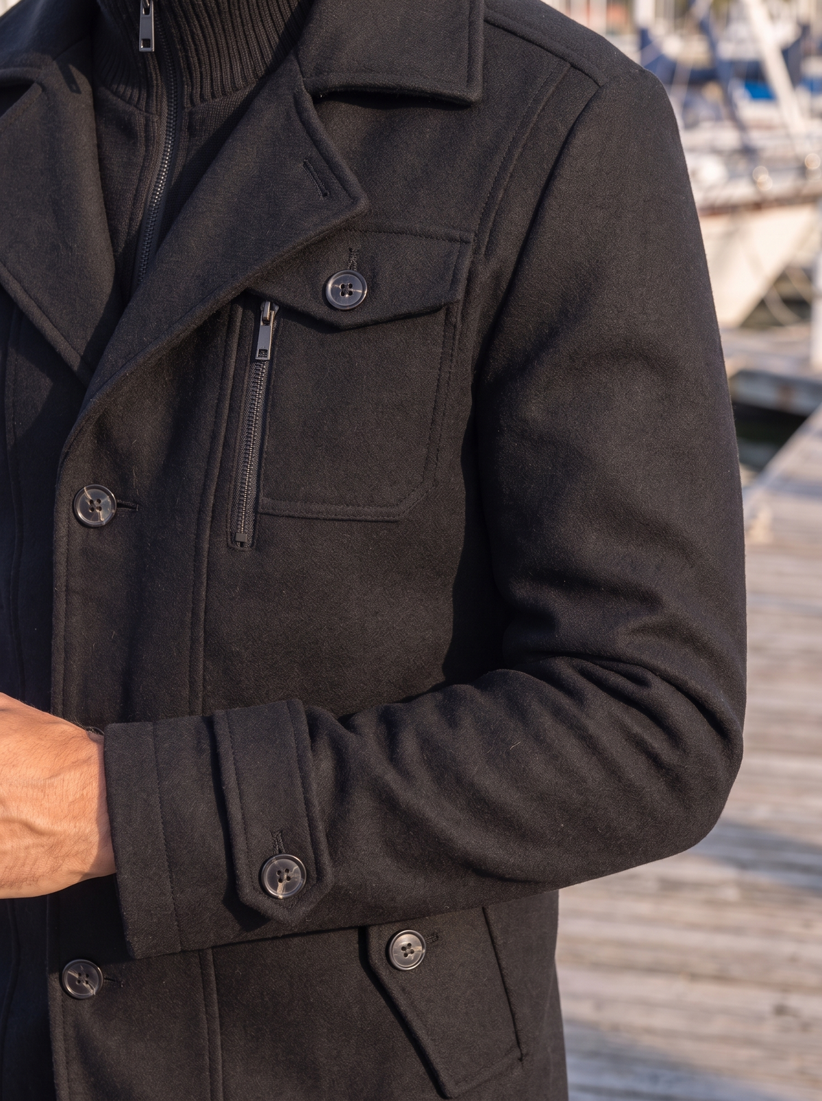 Close-up of the zip chest pocket and epaulette on the charcoal coat